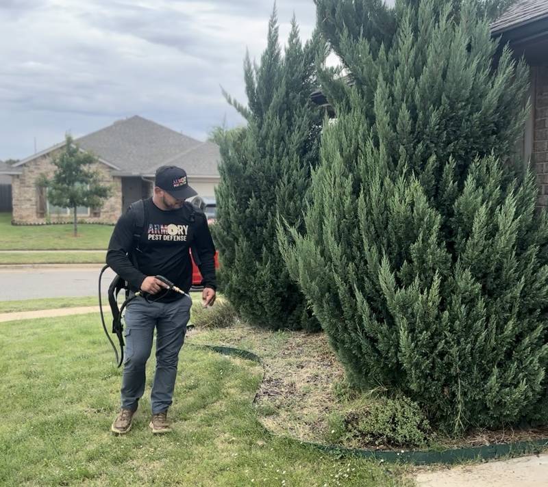 Technician spraying landscaping around a residential home